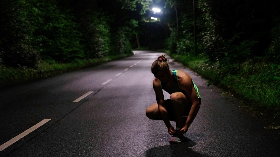 a woman squatting down on a road at night