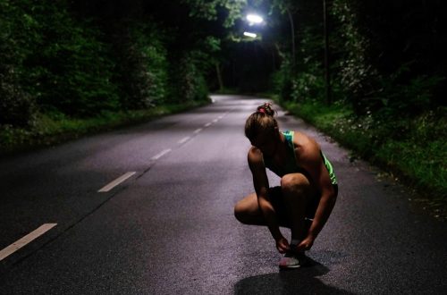 a woman squatting down on a road at night