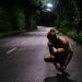 a woman squatting down on a road at night
