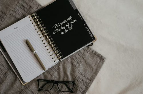 Stylish flatlay featuring a planner with quote, pen, and eyeglasses on a neutral background.